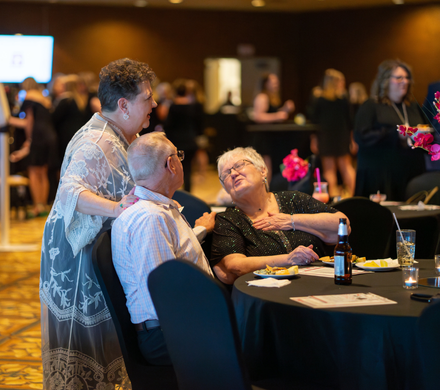 Three people engage in conversation at a busy event