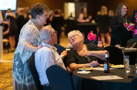 Three people engage in conversation at a busy event